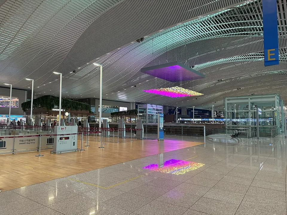 넓은 천장 아래 자동 수하물 위탁 안내판과 체크인 카운터가 있는 인천공항 제2여객터미널 출국장