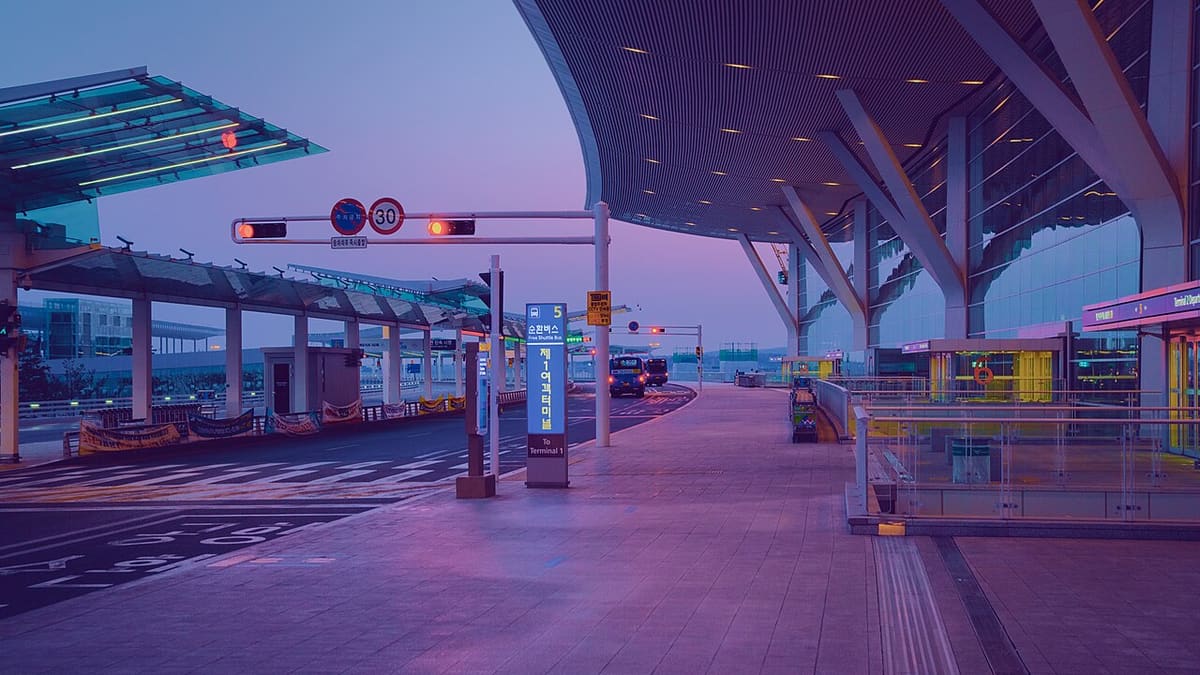 해가 뜨기 전 보랏빛 하늘 아래 인천공항 제2여객터미널 출국층 앞 도로와 순환버스 정류장